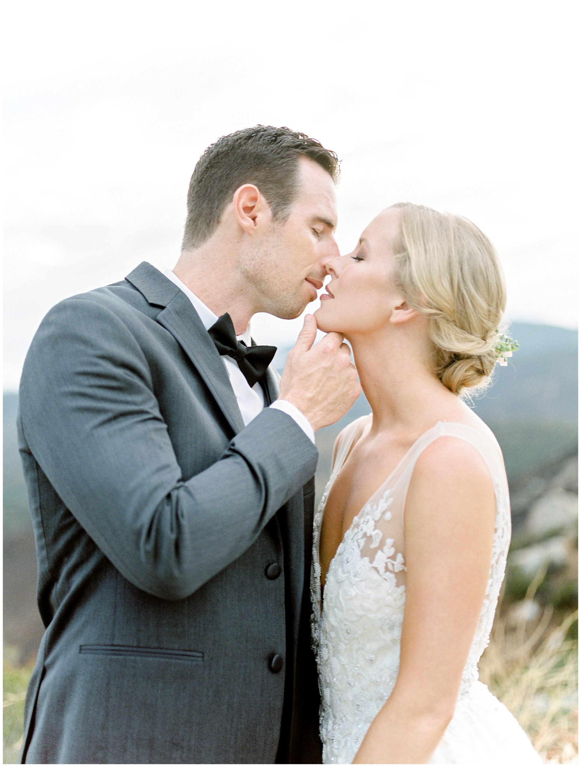 groom holding bride's chin to kiss
